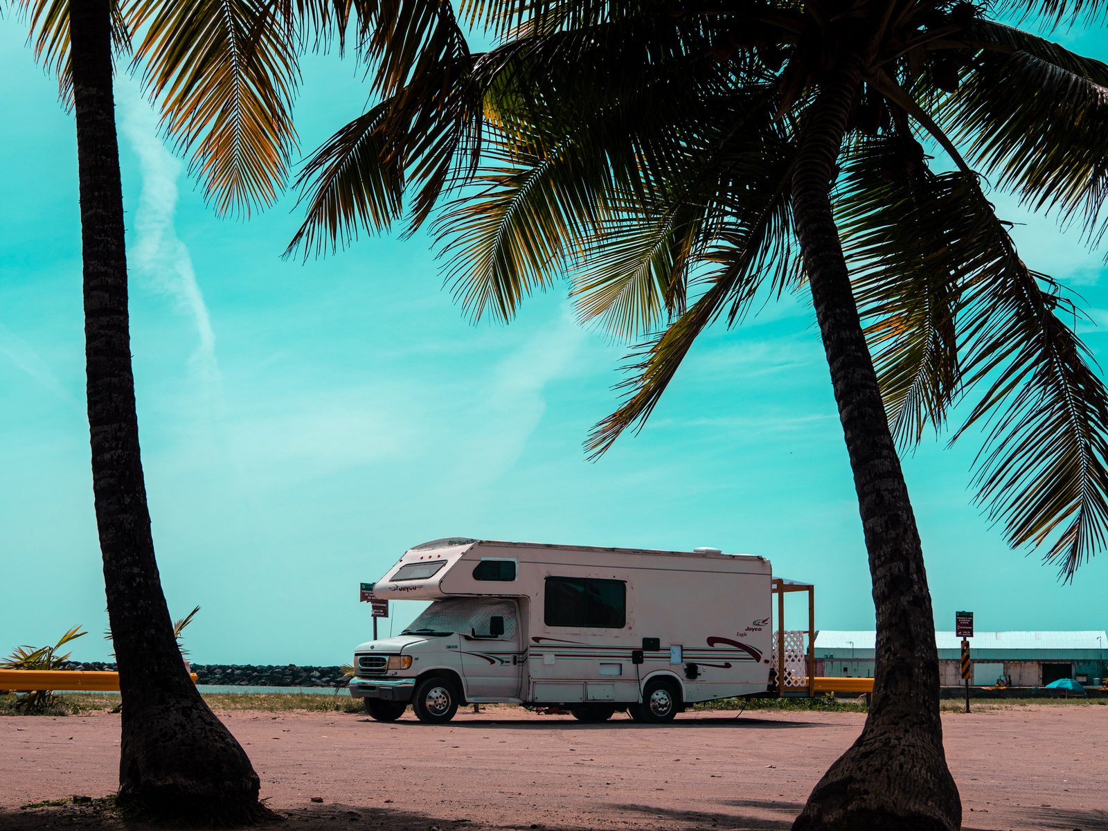El motorhome enmarcado entre dos palmeras con el mar de fondo